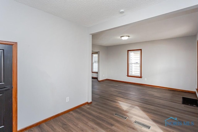 spare room with visible vents, a textured ceiling, baseboards, and wood finished floors