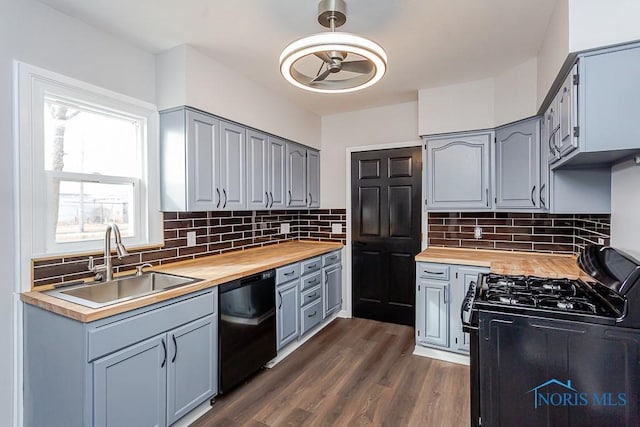 kitchen with dark wood-style flooring, gray cabinetry, black appliances, wooden counters, and a sink