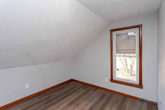 bonus room with dark wood-style floors, a textured ceiling, lofted ceiling, and baseboards