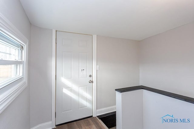 foyer entrance with dark wood finished floors and baseboards