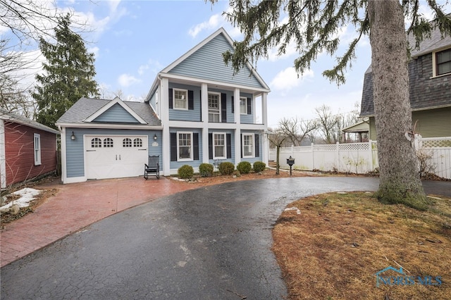 neoclassical / greek revival house featuring a shingled roof, driveway, an attached garage, and fence