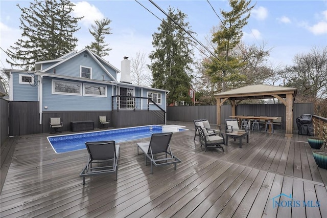 deck with a gazebo, area for grilling, fence, and a fenced in pool