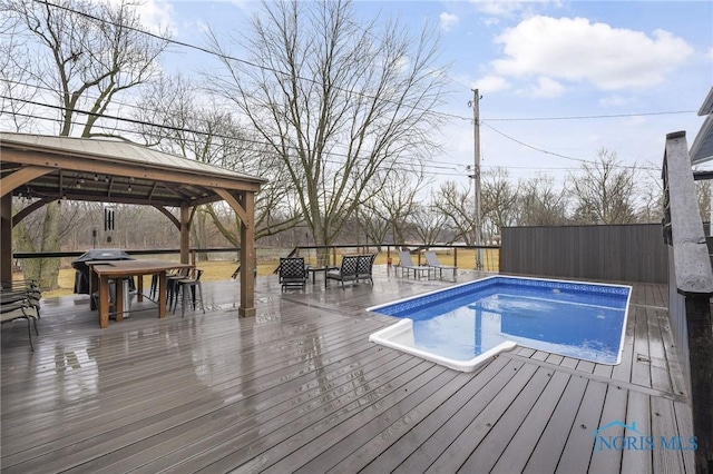 view of swimming pool featuring a fenced in pool, a wooden deck, a gazebo, and grilling area