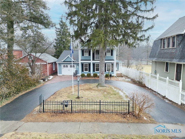 view of front of home with a fenced front yard, driveway, and an attached garage