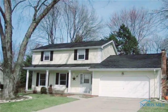 traditional home with a garage, covered porch, concrete driveway, and a front yard