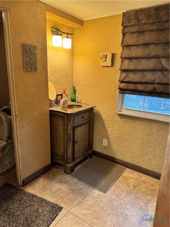 bathroom with a textured wall, tile patterned floors, and baseboards