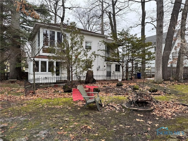 rear view of house with fence and a fire pit