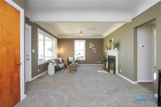 sitting room with baseboards, a fireplace with flush hearth, carpet, and beam ceiling