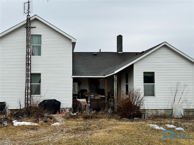 rear view of house featuring a shingled roof and a chimney