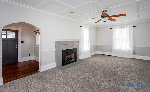 unfurnished living room featuring a fireplace with flush hearth, arched walkways, coffered ceiling, and plenty of natural light