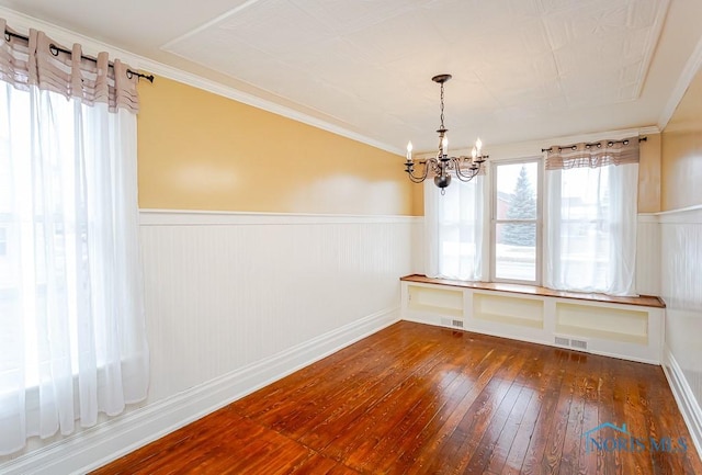 unfurnished dining area featuring a wainscoted wall, dark wood-style flooring, and visible vents