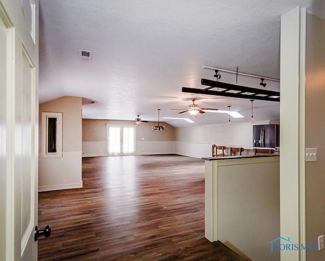 interior space featuring vaulted ceiling, ceiling fan, a textured ceiling, and wood finished floors