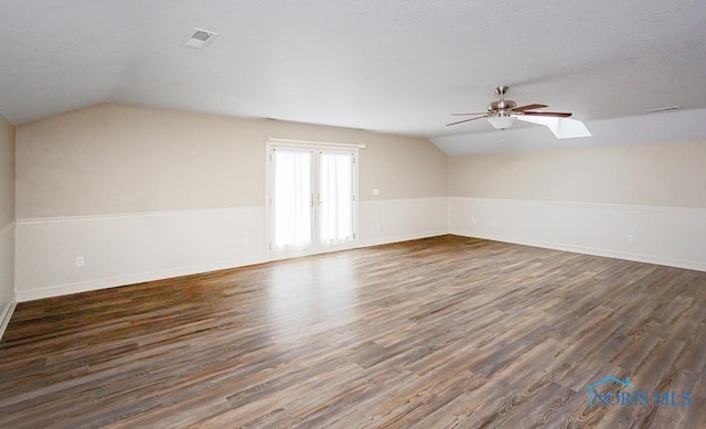 bonus room featuring lofted ceiling with skylight, visible vents, dark wood finished floors, and a ceiling fan
