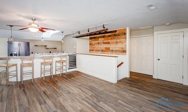 kitchen featuring light countertops, visible vents, beverage cooler, stainless steel fridge, and a peninsula
