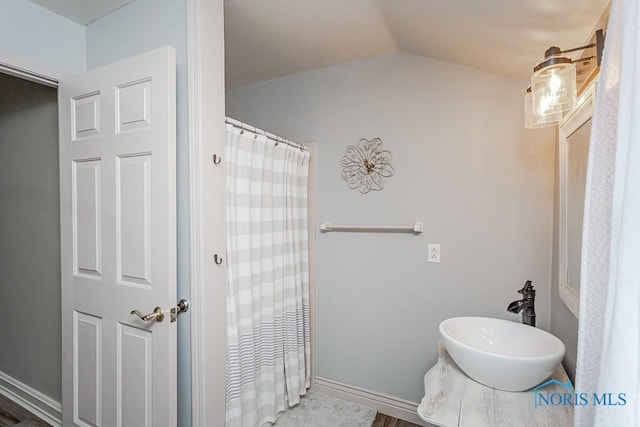 bathroom featuring lofted ceiling, baseboards, and a sink