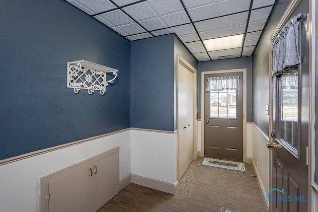 doorway with a drop ceiling and baseboards