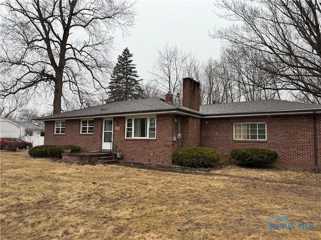 single story home with brick siding, a chimney, and a front yard