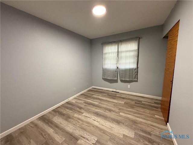 unfurnished room featuring baseboards and wood finished floors