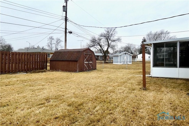 view of yard featuring a storage shed, an outdoor structure, fence, and a sunroom