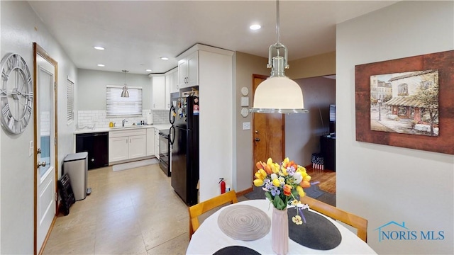 kitchen featuring pendant lighting, tasteful backsplash, white cabinets, a sink, and black appliances