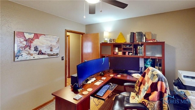 office area with ceiling fan, baseboards, and a textured wall