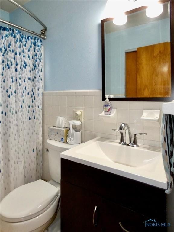 bathroom featuring a shower with shower curtain, vanity, toilet, and tile walls