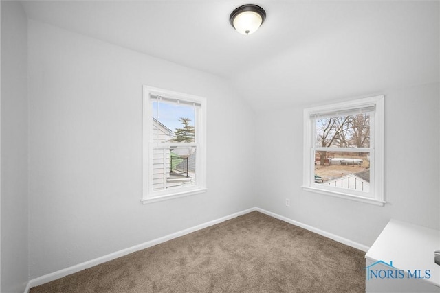 empty room featuring lofted ceiling, carpet, and baseboards