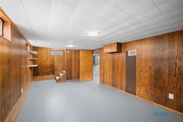 unfurnished room with finished concrete floors, visible vents, and wooden walls