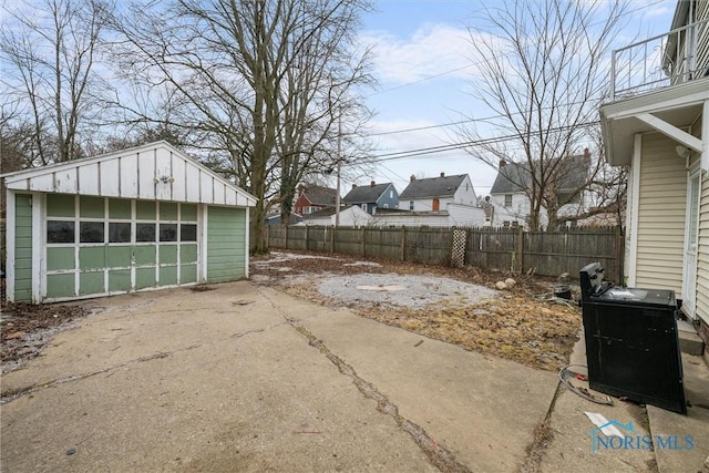 exterior space with a garage, concrete driveway, an outdoor structure, and fence