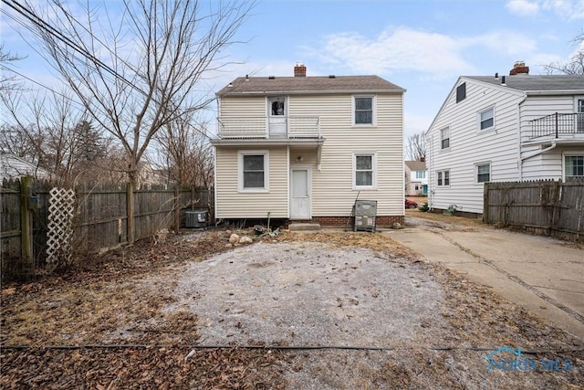 back of house with a chimney, fence, and cooling unit