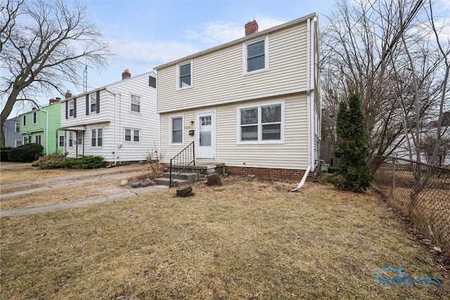 colonial home with a chimney, a front yard, and fence