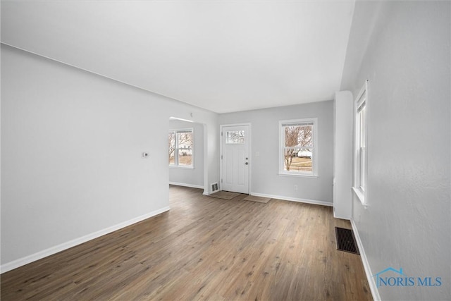 unfurnished living room featuring wood finished floors, visible vents, and baseboards