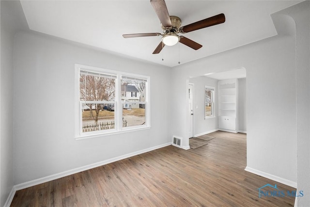 spare room featuring a ceiling fan, wood finished floors, visible vents, and baseboards