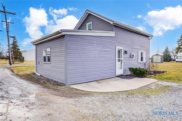 view of side of property with an outbuilding, a patio area, driveway, and a storage unit