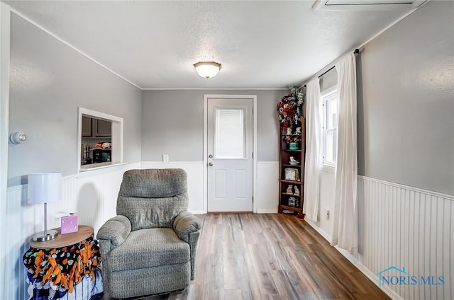 sitting room featuring a wainscoted wall, a textured ceiling, and wood finished floors