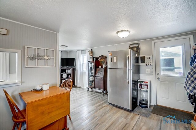 kitchen featuring freestanding refrigerator, a textured ceiling, and light wood finished floors