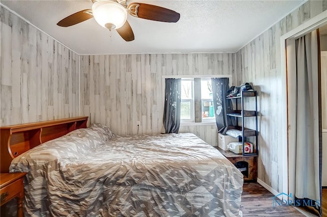 bedroom with a ceiling fan, a textured ceiling, and wood finished floors