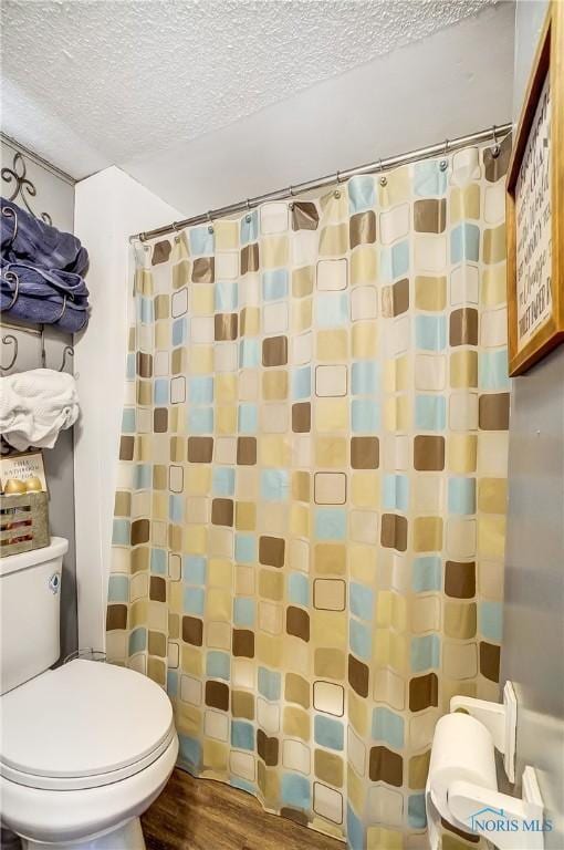 bathroom featuring a textured ceiling, curtained shower, wood finished floors, and toilet