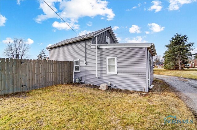 view of side of home featuring fence and a lawn