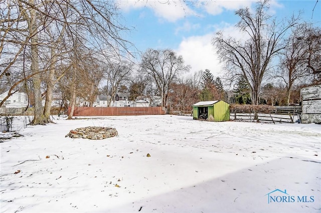 yard covered in snow featuring an outbuilding, fence, and a storage shed