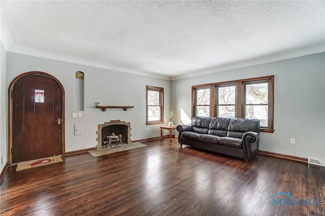 living room with arched walkways, dark wood-style flooring, visible vents, a textured ceiling, and baseboards