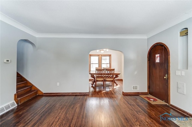 entrance foyer featuring arched walkways, dark wood finished floors, visible vents, and baseboards