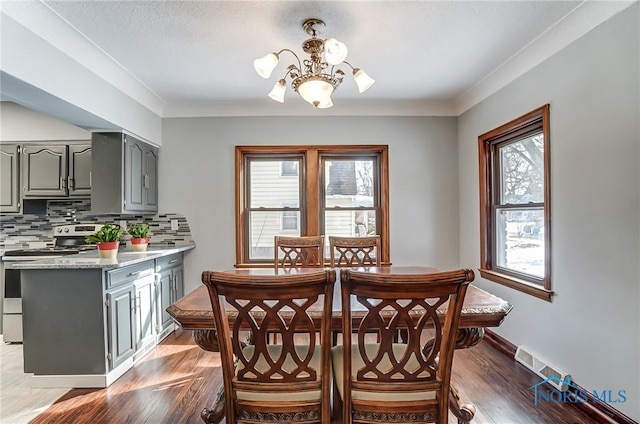 dining space featuring baseboards, a chandelier, dark wood-type flooring, and ornamental molding