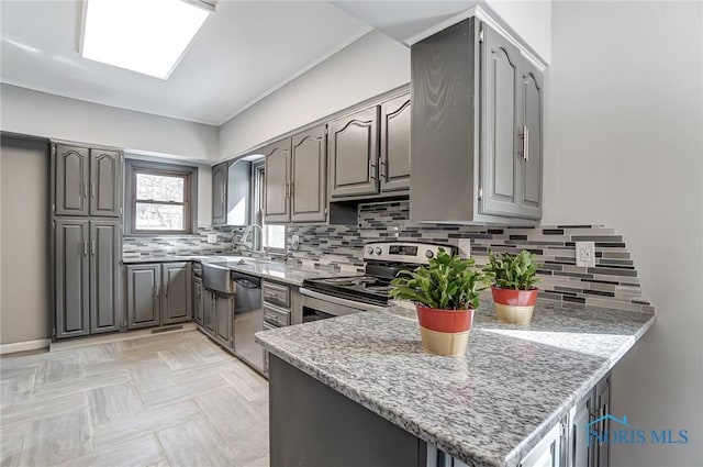 kitchen featuring a peninsula, tasteful backsplash, appliances with stainless steel finishes, and gray cabinetry