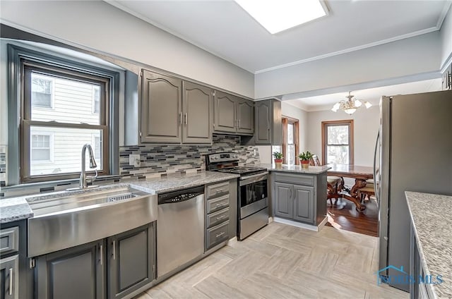 kitchen with decorative backsplash, light stone countertops, gray cabinets, crown molding, and stainless steel appliances