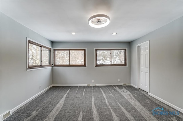 carpeted spare room featuring visible vents and baseboards