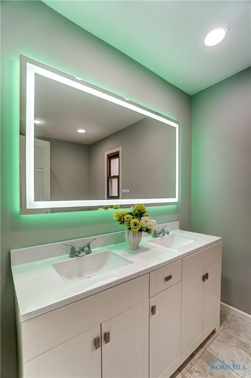 bathroom featuring double vanity, a sink, and baseboards