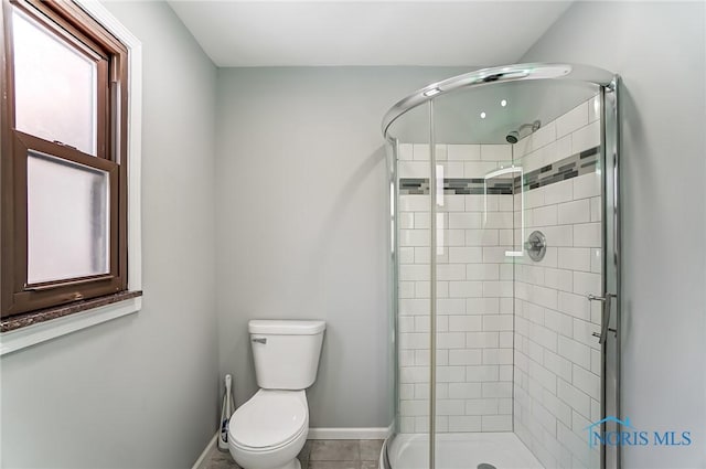 bathroom featuring a shower stall, toilet, and baseboards