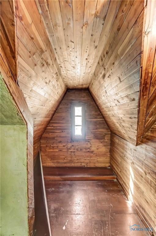 bonus room with lofted ceiling, wooden ceiling, wooden walls, and dark wood-style floors