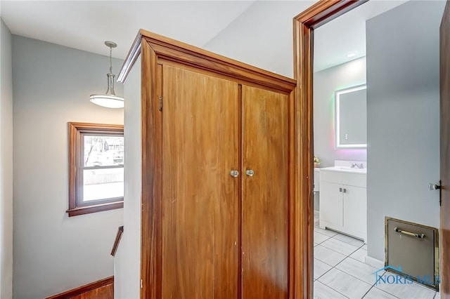 interior space with light tile patterned flooring, a sink, and baseboards